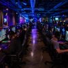 Busy LAN gaming center at night with rows of gaming PCs fully operational