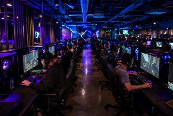 Busy LAN gaming center at night with rows of gaming PCs fully operational
