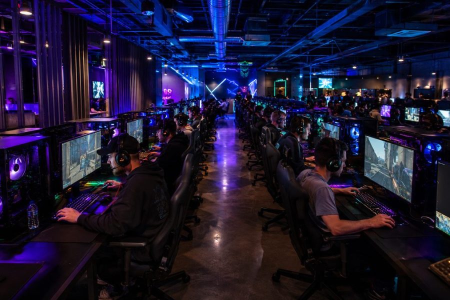 Busy LAN gaming center at night with rows of gaming PCs fully operational