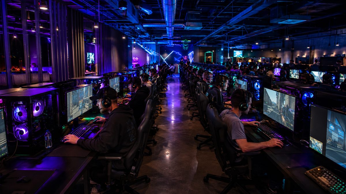 Busy LAN gaming center at night with rows of gaming PCs fully operational