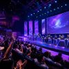 Collegiate esports tournament in an auditorium with players on stage and a cheering crowd